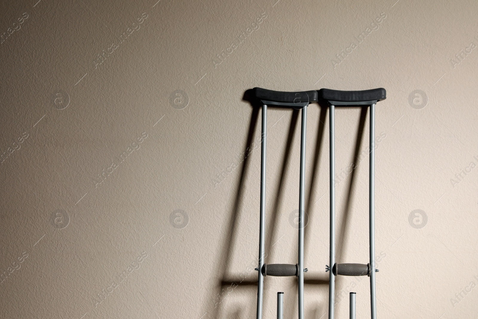 Photo of Pair of axillary crutches on beige background. Space for text