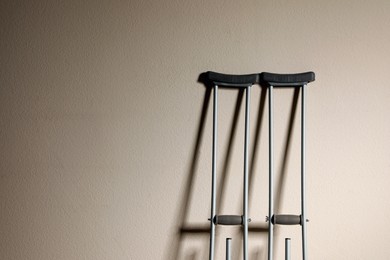 Pair of axillary crutches on beige background. Space for text