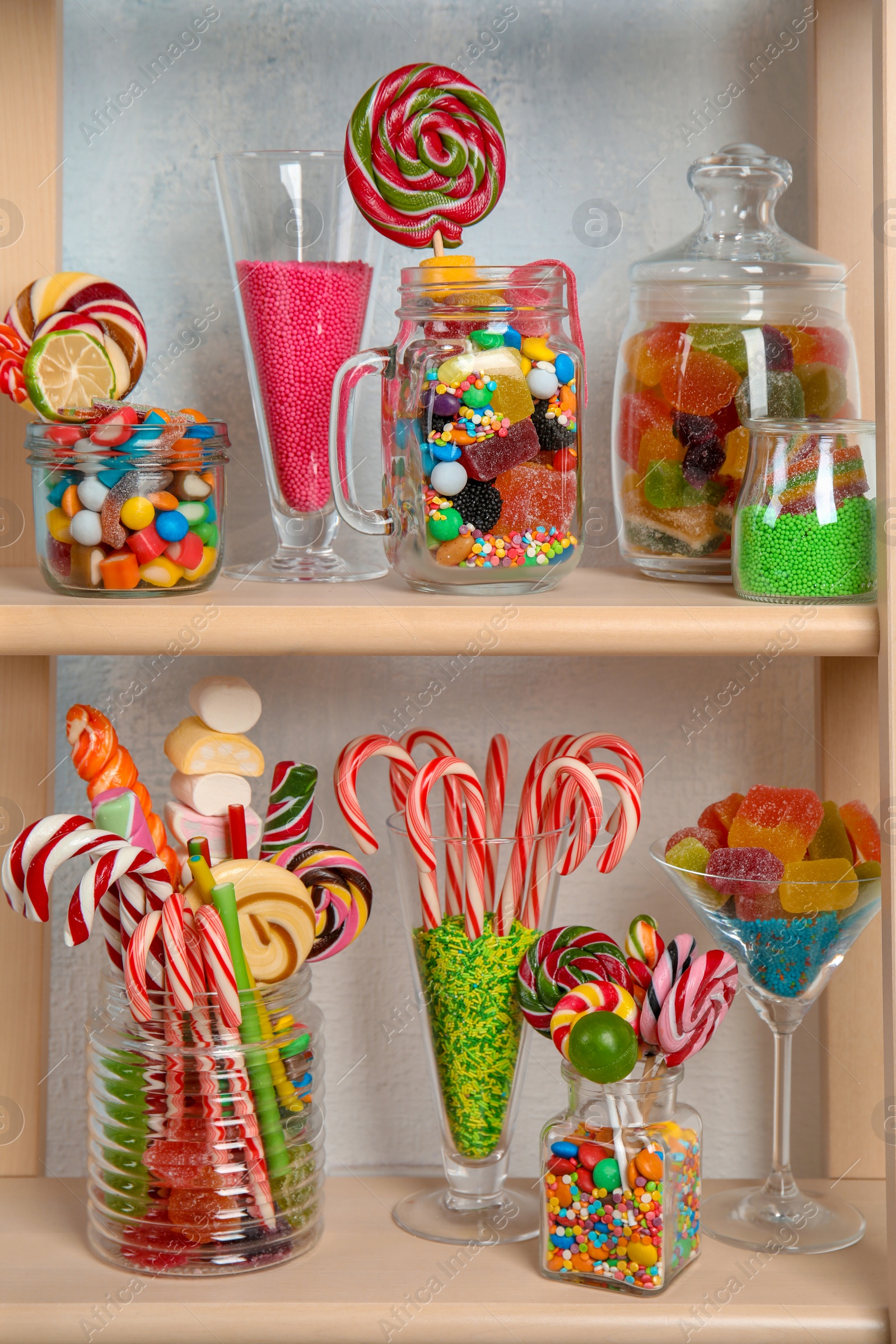 Photo of Many different yummy candies on wooden shelves