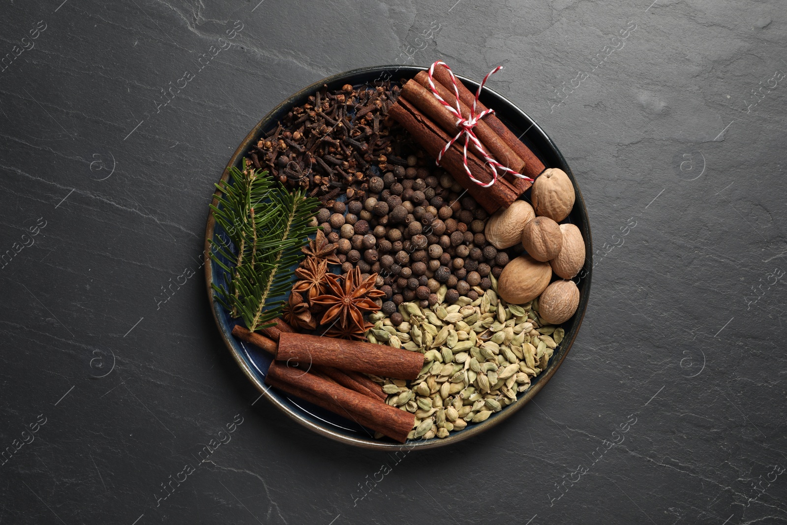 Photo of Different spices, nuts and fir branches on dark gray textured table, top view