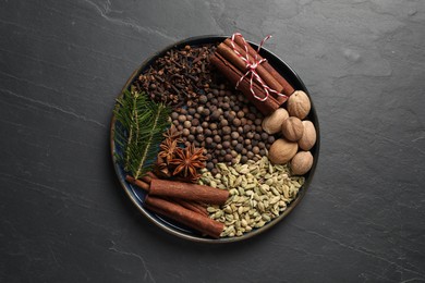 Photo of Different spices, nuts and fir branches on dark gray textured table, top view