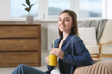 Photo of Beautiful young woman with delicious smoothie at home. Space for text