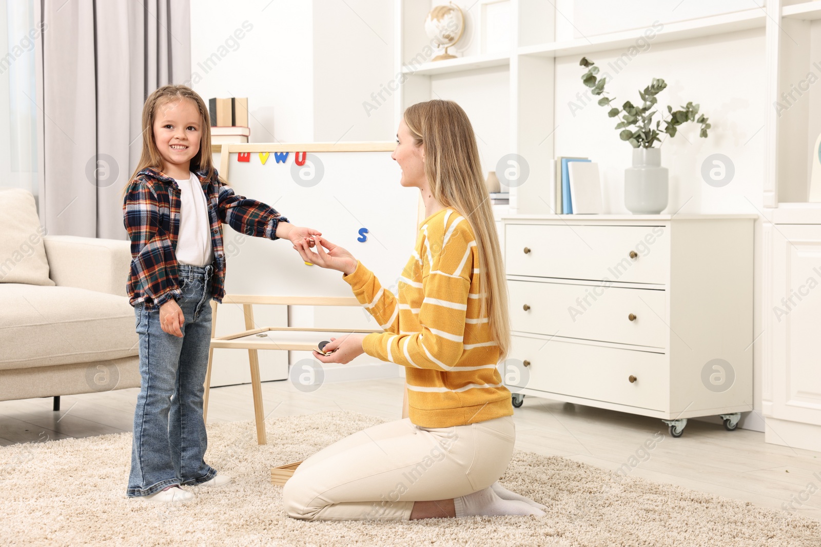 Photo of Mom teaching her daughter alphabet with magnetic letters at home