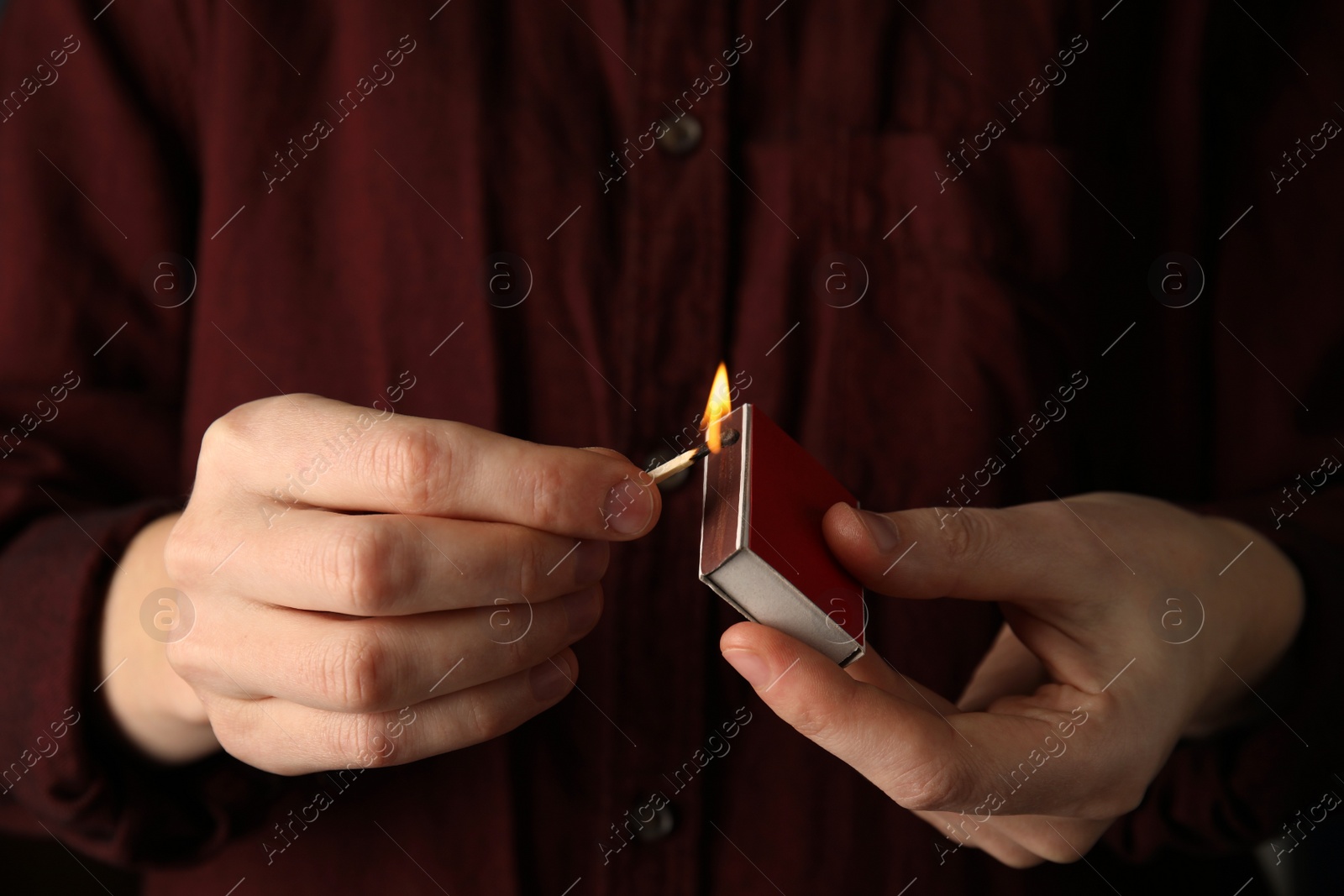 Photo of Man with box and burning match, closeup