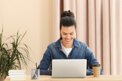 Smiling African American woman working on laptop at table indoors