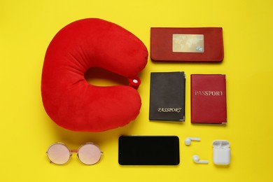 Photo of Flat lay composition with red travel pillow and smartphone on yellow background