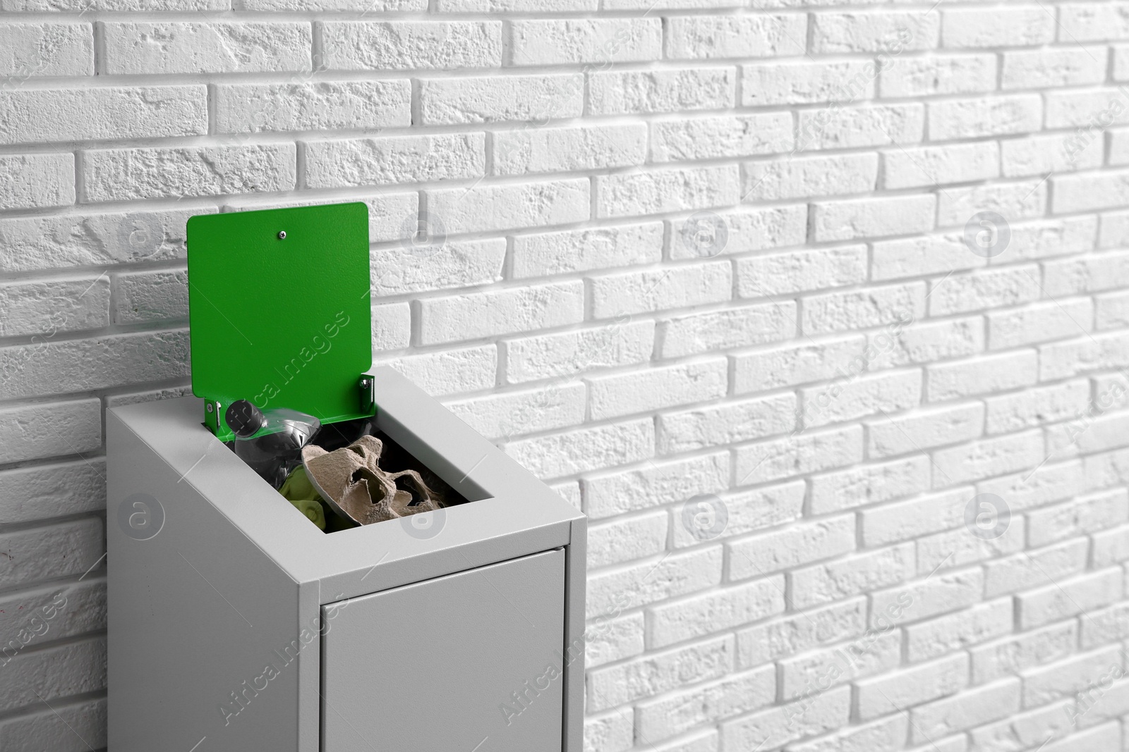 Photo of Overfilled trash bin near brick wall, space for text. Recycling concept