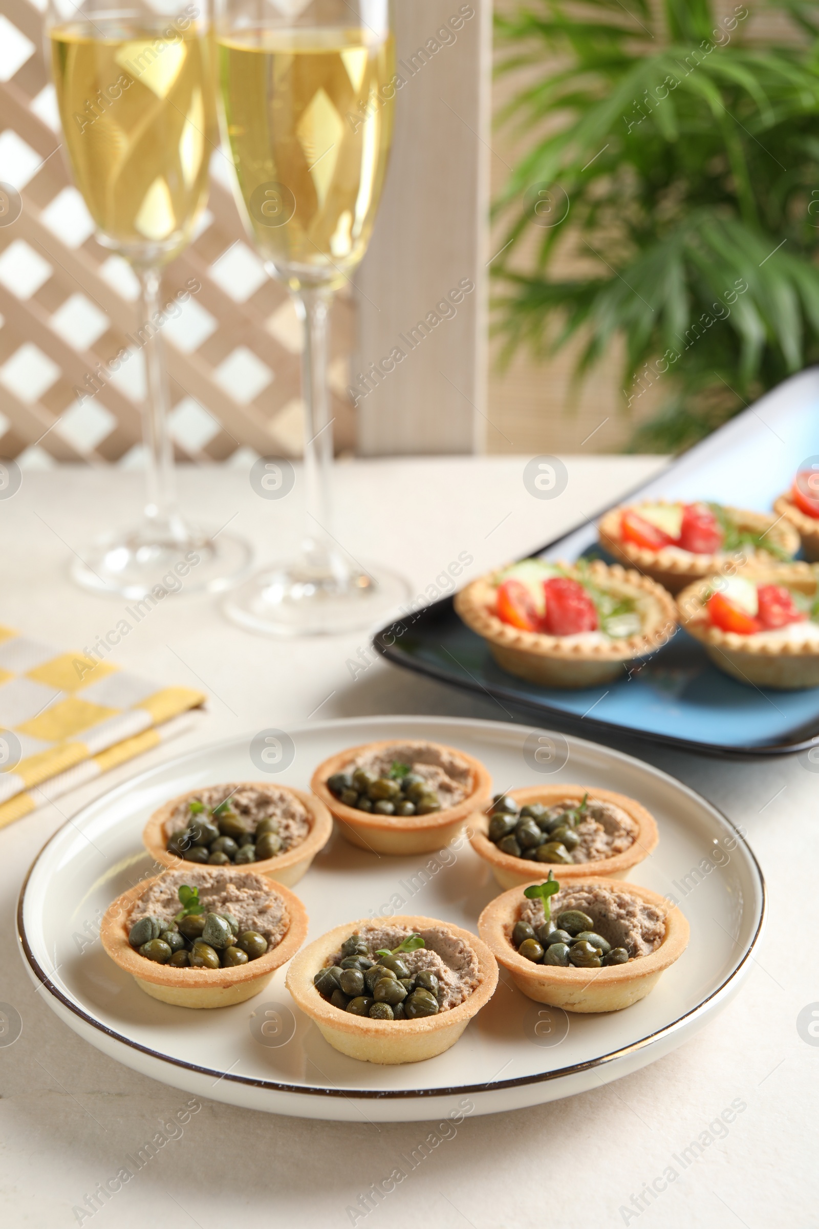 Photo of Delicious canapes with pate and capers served on white table