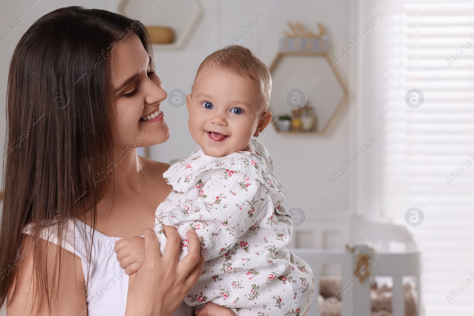 Photo of Happy young mother with her baby daughter in nursery. Space for text