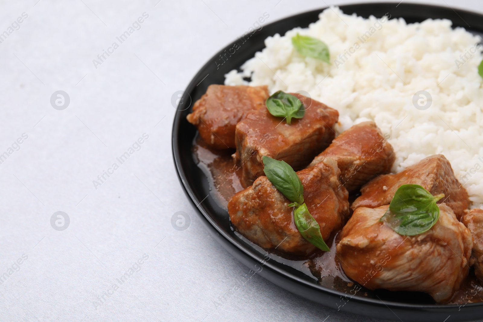 Photo of Delicious goulash with rice on light table, closeup. Space for text