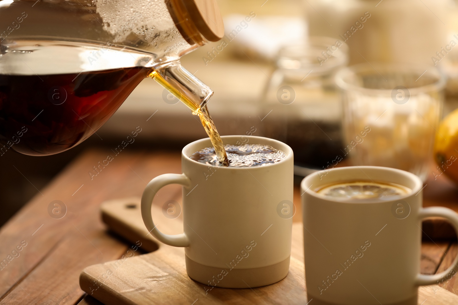 Photo of Pouring delicious tea into cup on wooden table, closeup