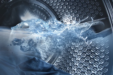Image of Washing machine drum with water and clothes, closeup view