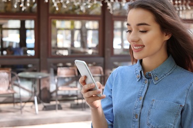 Photo of Young woman using mobile phone outdoors