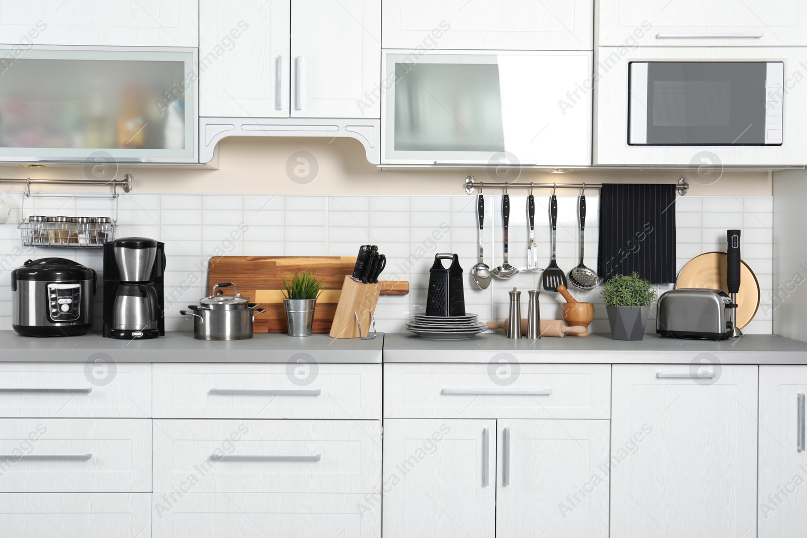 Photo of Different appliances, clean dishes and utensils on kitchen counter