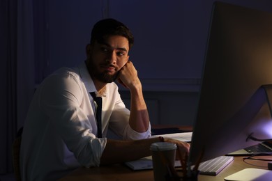 Photo of Tired young man working late in office