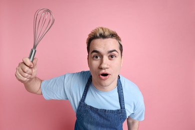 Photo of Portrait of emotional confectioner holding whisk on pink background