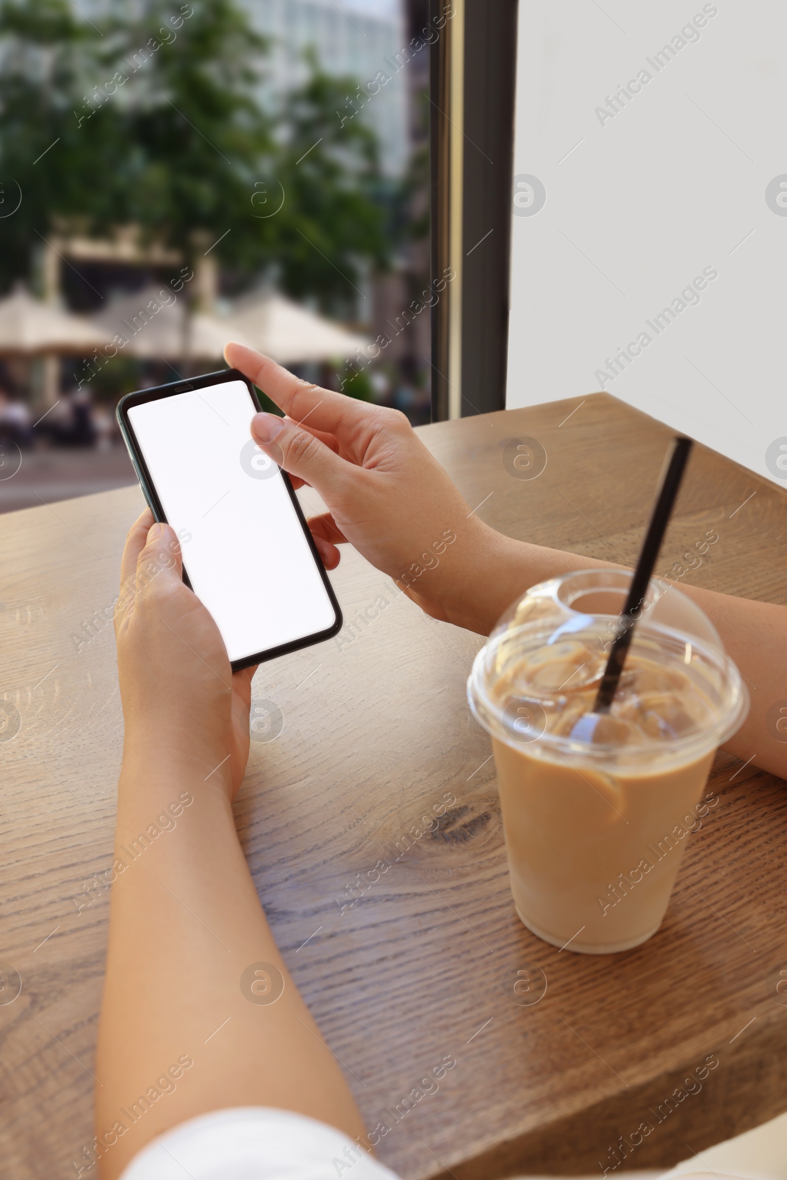 Photo of Woman using smartphone near window in cafe, closeup