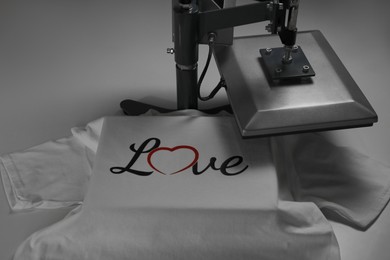 Photo of Printing logo. Heat press with t-shirt on white table