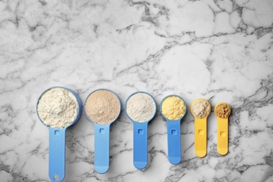 Photo of Scoops with different types of flour on marble background