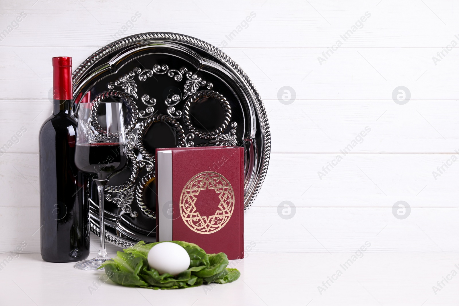 Photo of Symbolic Pesach (Passover Seder) items on white table, space for text