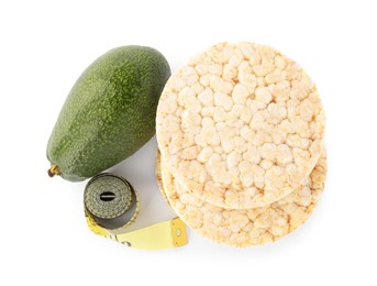 Photo of Healthy diet. Stack of puffed rice cakes, avocado and measuring tape isolated on white, top view