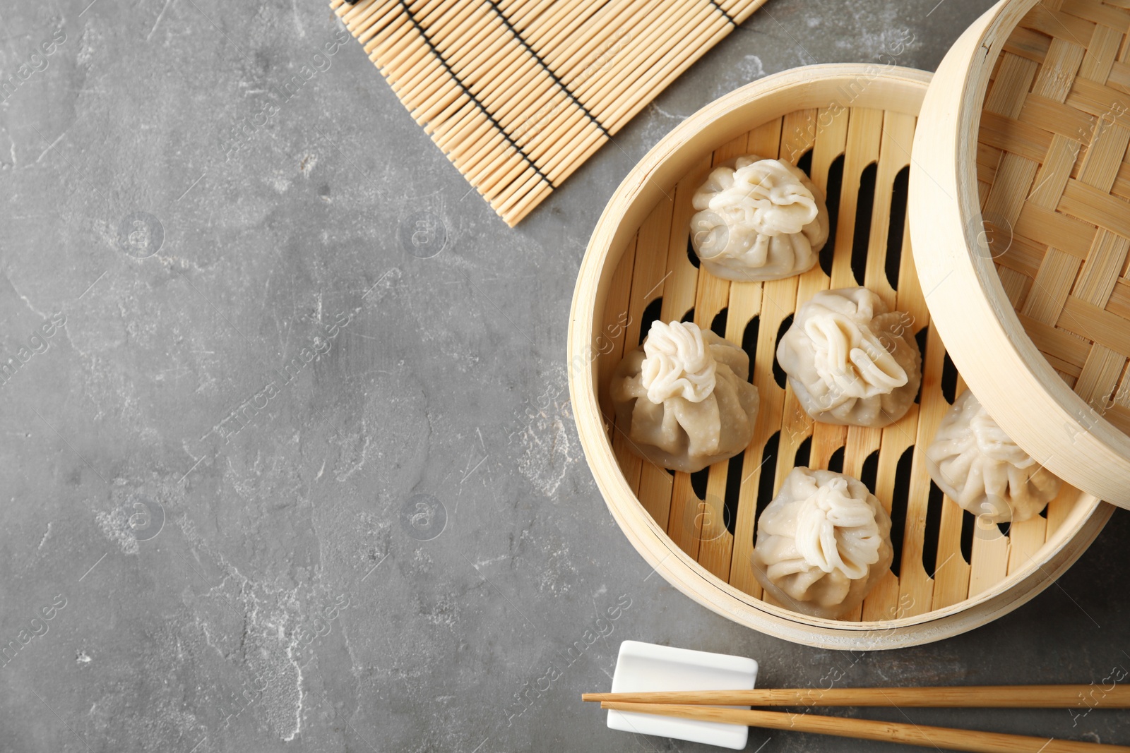 Photo of Bamboo steamer with tasty baozi dumplings on table, top view. Space for text