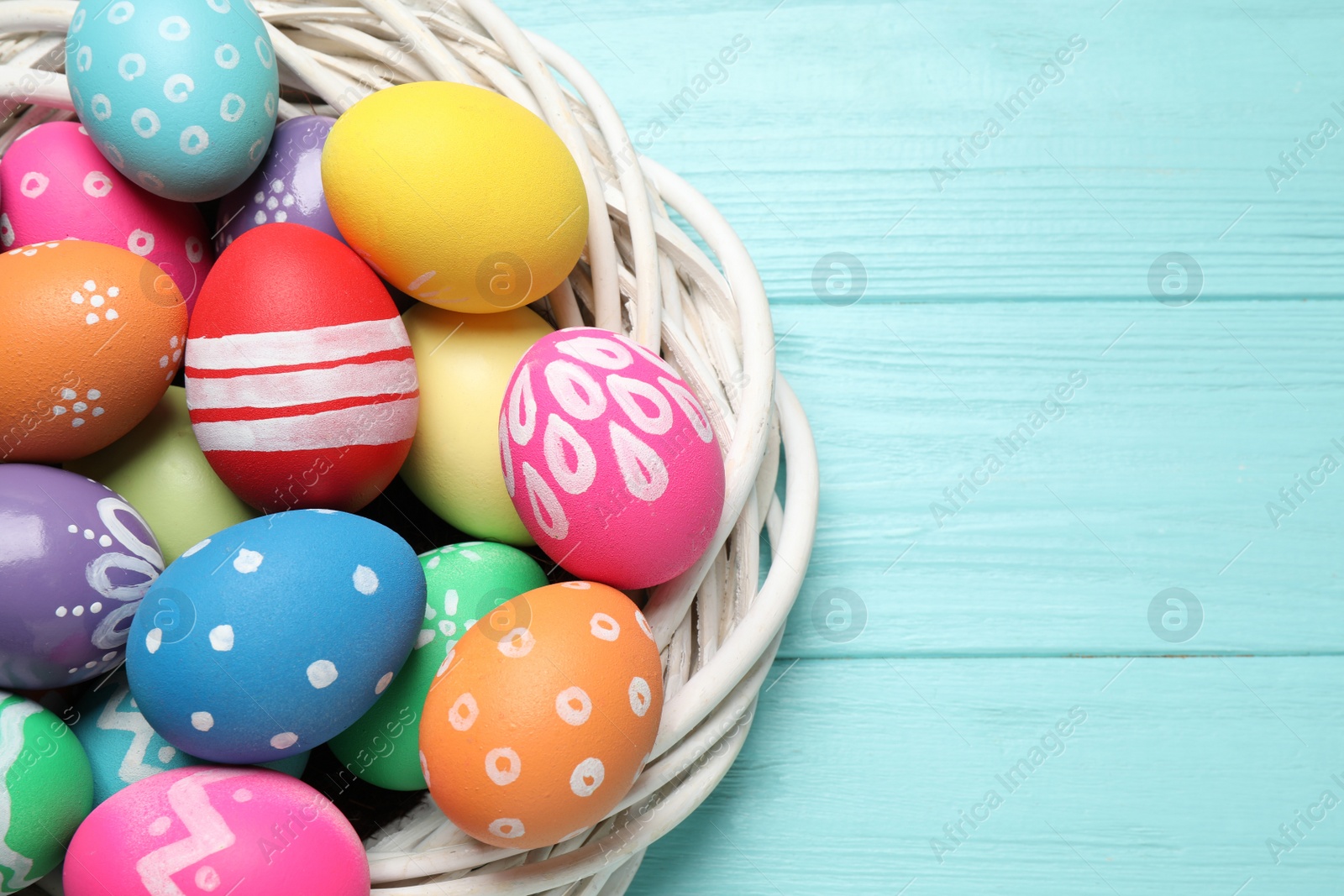 Photo of Colorful Easter eggs on light blue wooden background, top view. Space for text