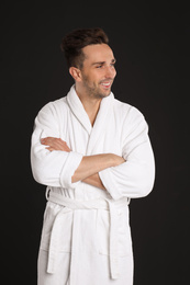 Photo of Happy young man in bathrobe on black background