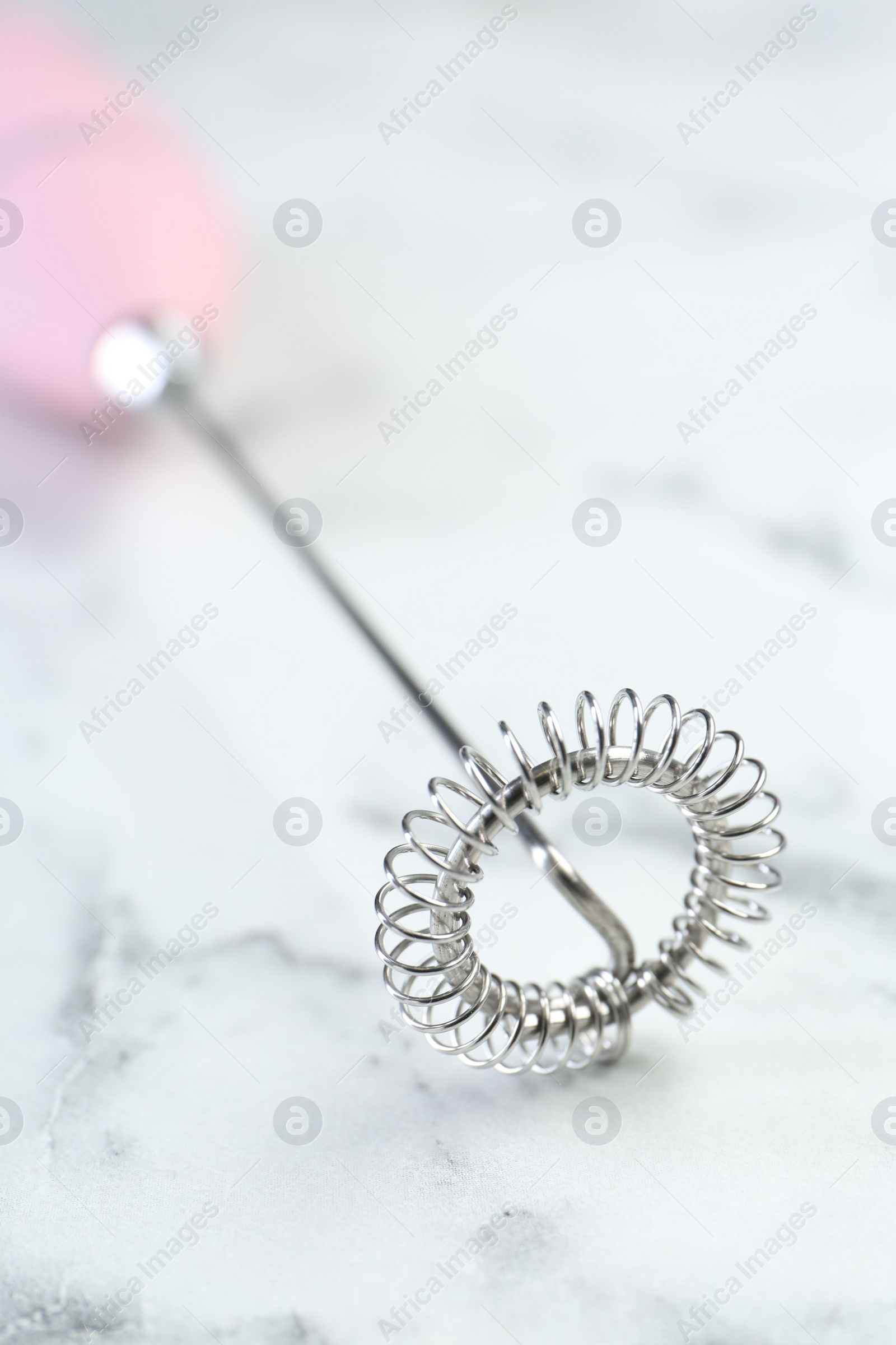 Photo of Pink milk frother wand on white marble table, closeup