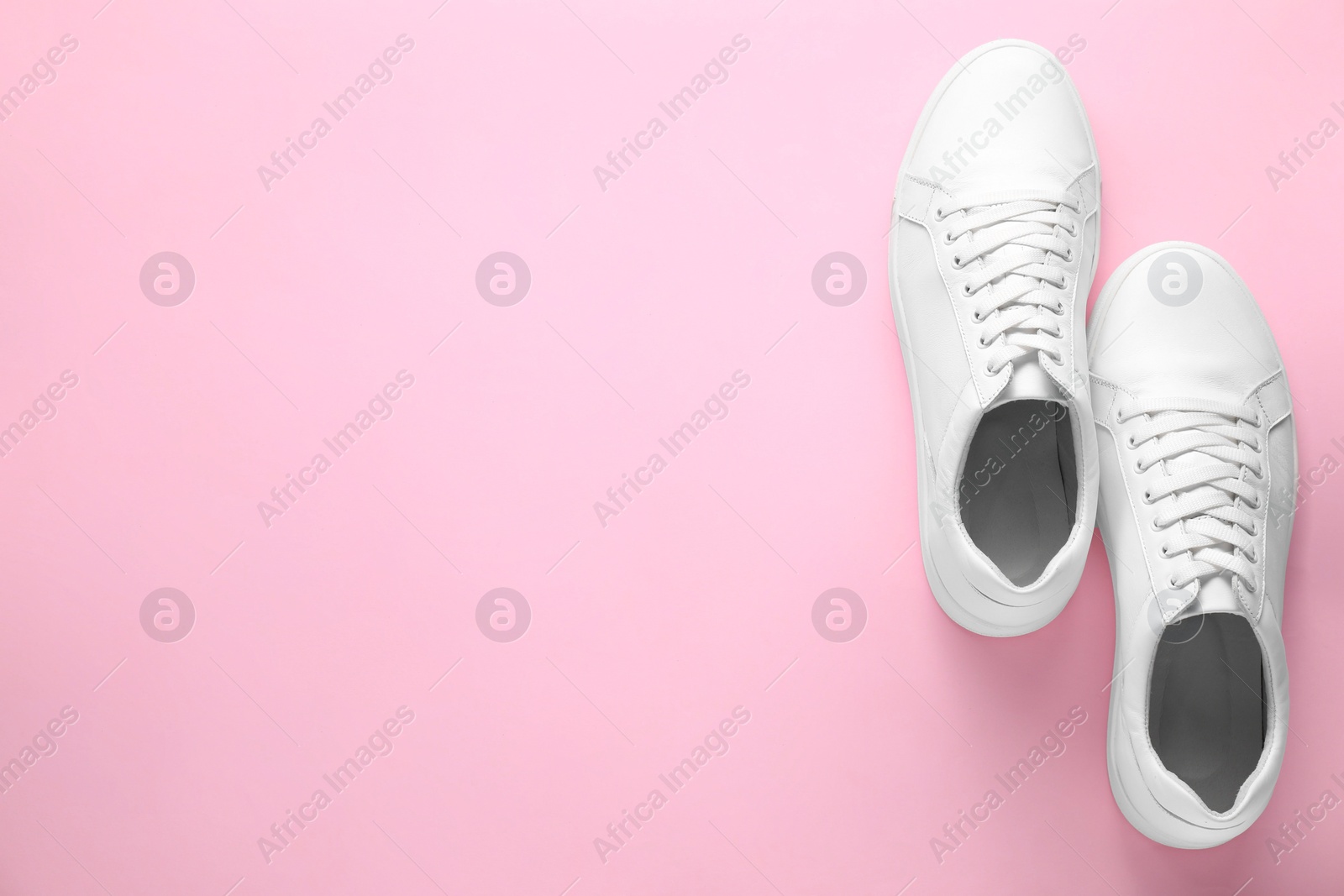 Photo of Pair of stylish white sneakers on pink background, top view. Space for text