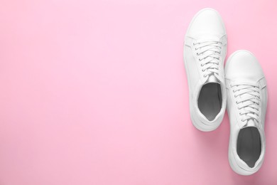 Photo of Pair of stylish white sneakers on pink background, top view. Space for text