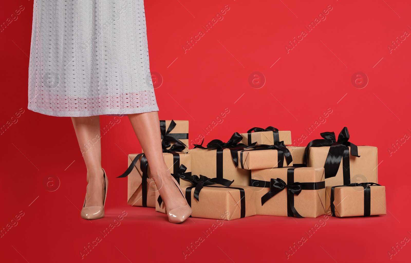 Photo of Woman and gift boxes on red background, closeup. Black Friday