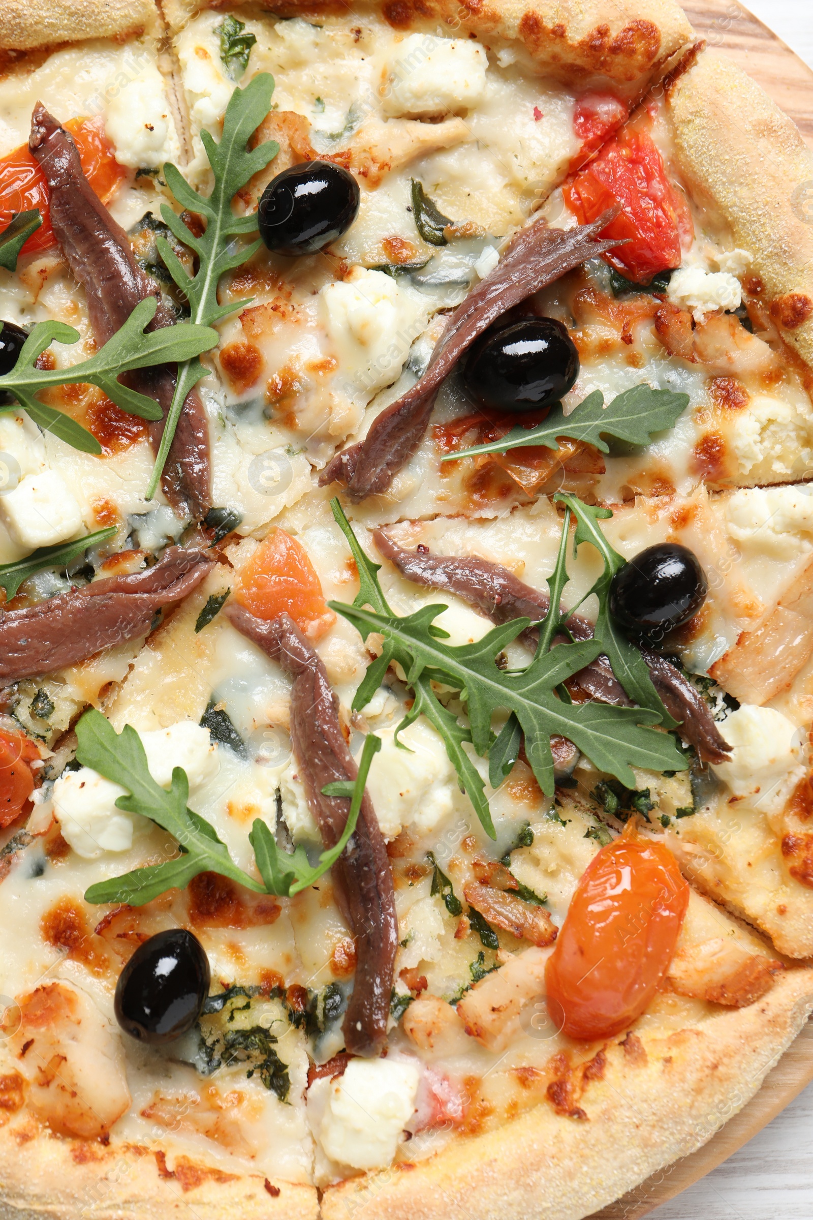 Photo of Tasty pizza with anchovies, arugula and olives, top view