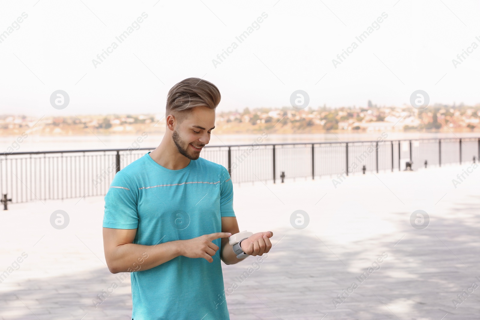 Photo of Young man checking pulse outdoors on sunny day