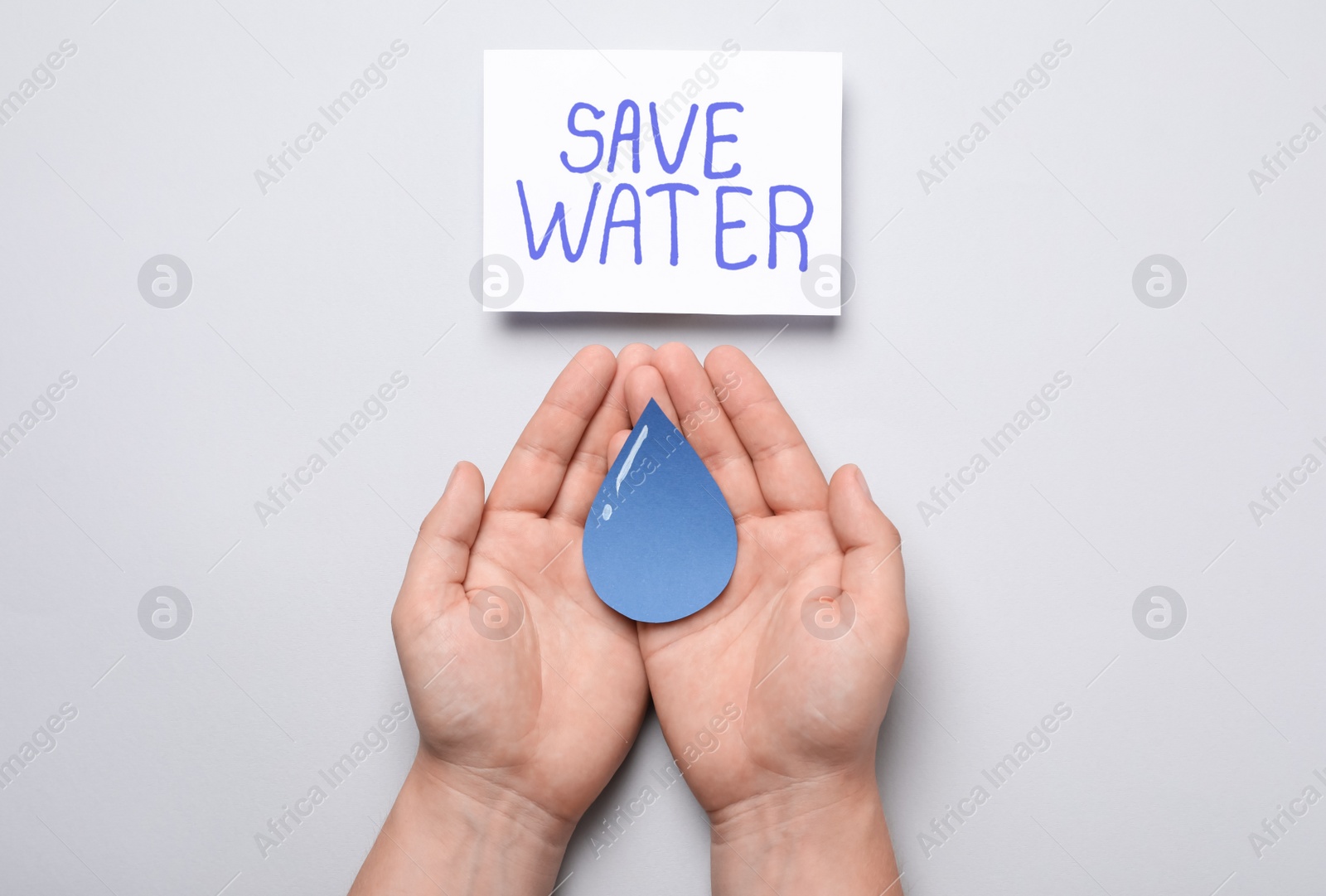 Photo of Man holding paper drop near card with words Save Water on light grey background, top view