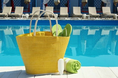 Beach accessories on wooden deck near swimming pool. Space for text