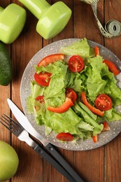 Photo of Healthy diet. Salad, cutlery, dumbbells and measuring tape on wooden table, flat lay