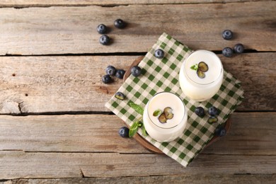 Photo of Composition with tasty yogurt in glasses and blueberries on wooden table, top view. Space for text