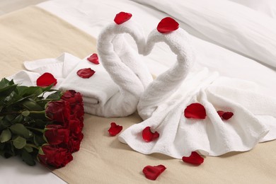Photo of Honeymoon. Swans made of towels and beautiful red roses on bed