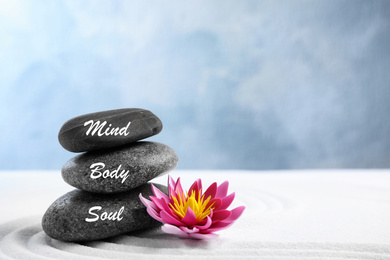 Photo of Stones with words Mind, Body, Soul and lotus flower on white sand. Zen garden