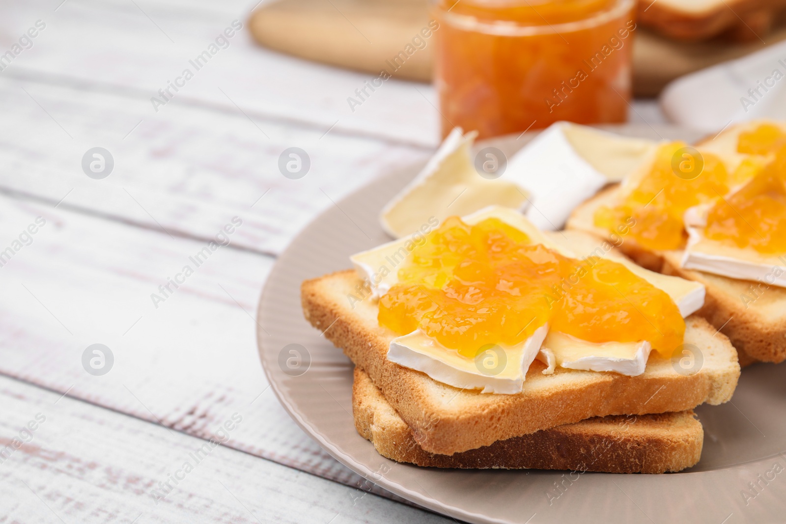 Photo of Tasty sandwiches with brie cheese and apricot jam on white wooden table, closeup. Space for text