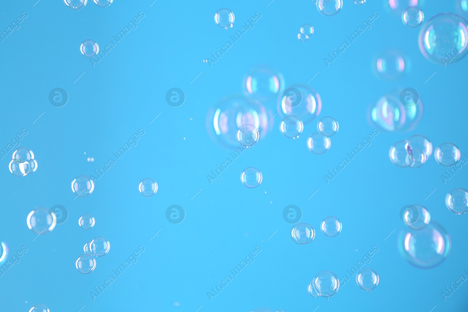 Photo of Beautiful transparent soap bubbles on light blue background