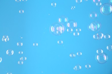 Photo of Beautiful transparent soap bubbles on light blue background