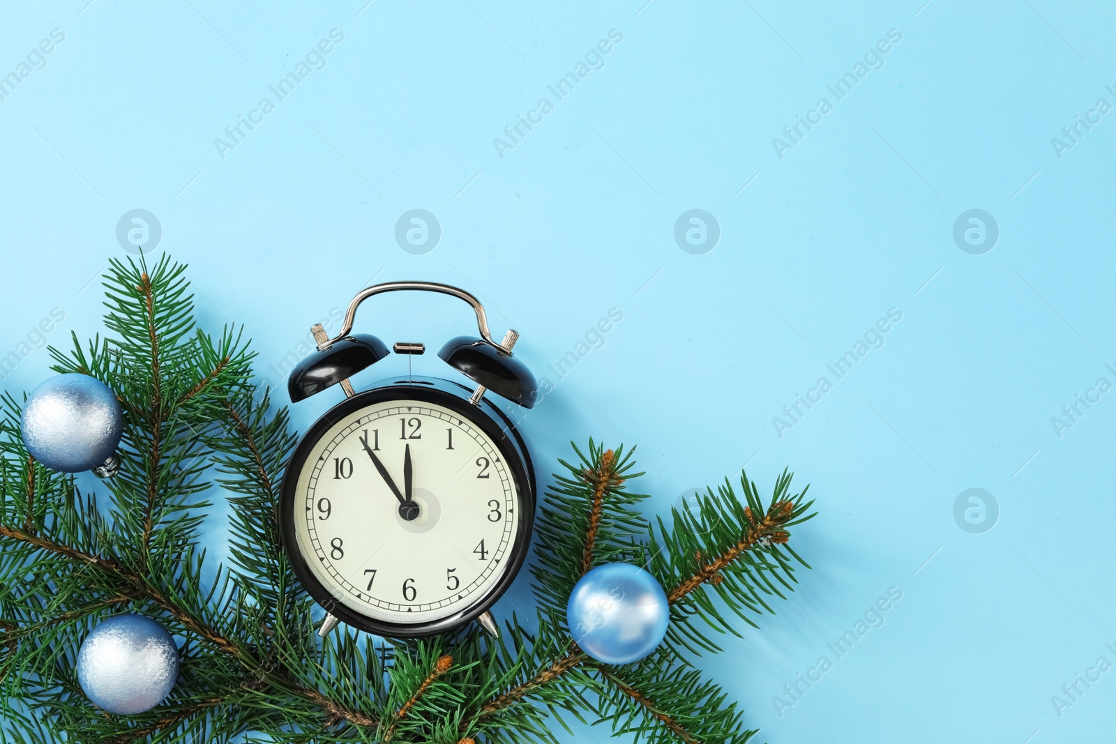 Photo of Alarm clock and decorated fir branch on light blue background, flat lay with space for text. New Year countdown