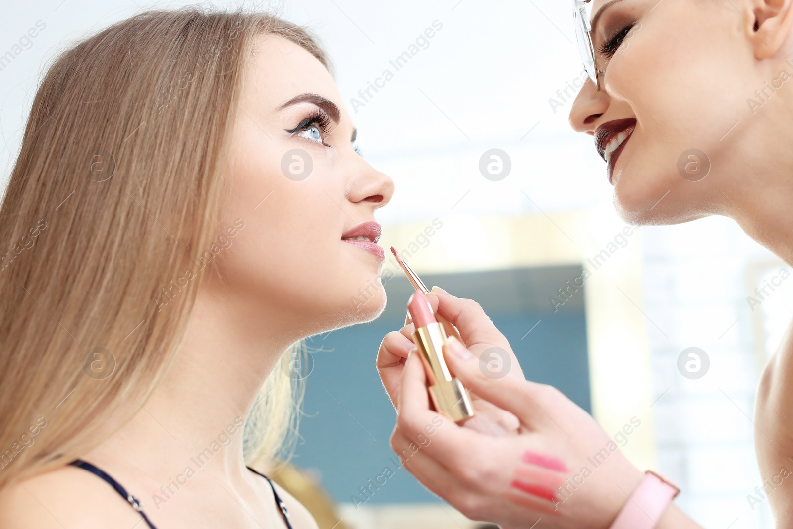 Photo of Professional makeup artist working with beautiful young woman in studio