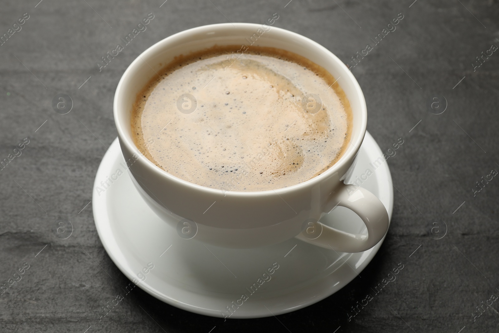 Photo of Cup of aromatic coffee on black table, closeup
