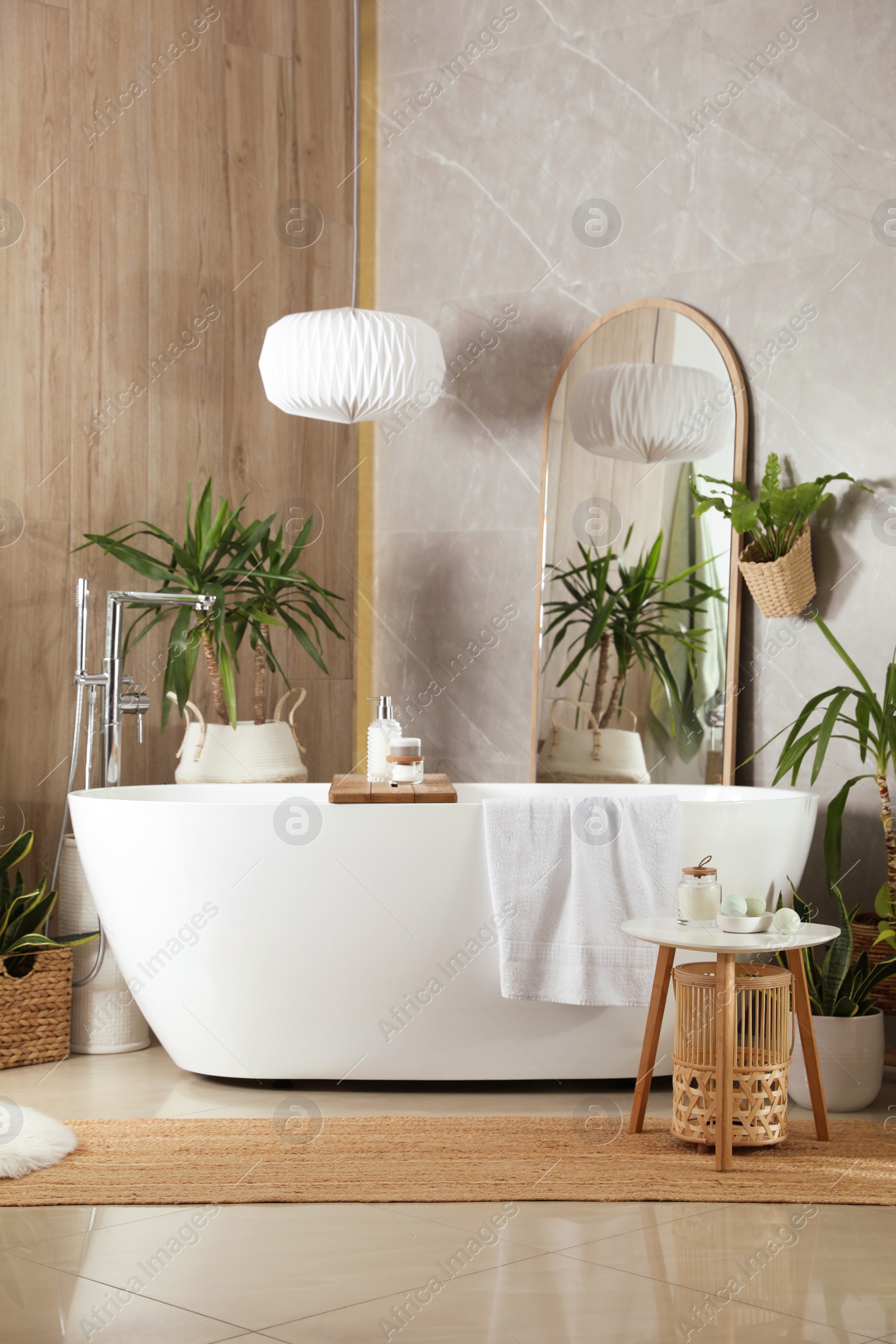 Photo of Modern white tub and beautiful green houseplants in bathroom. Interior design