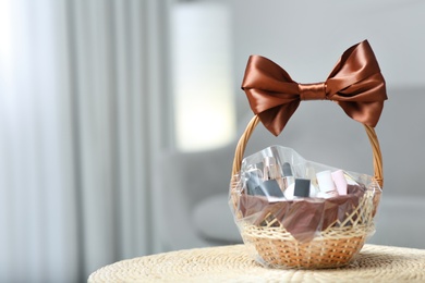 Photo of Wicker basket full of gifts in living room. Space for text