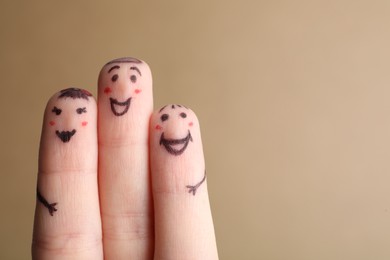 Photo of Three fingers with drawings of happy faces on brown background, space for text