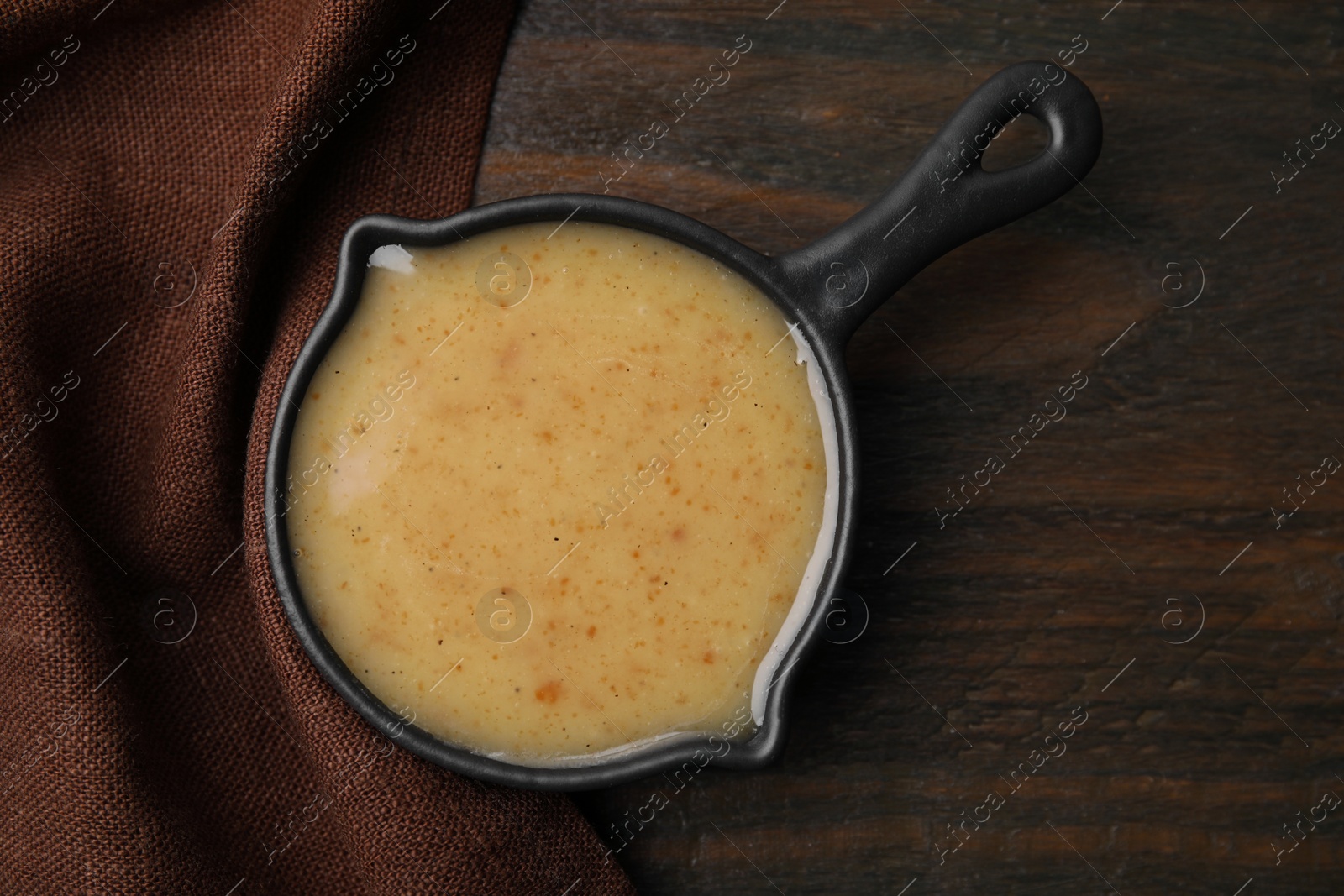 Photo of Delicious turkey gravy in saucepan on wooden table, top view